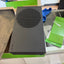 A black Xbox Series S console sitting on its green and white retail box on a glass countertop in a store setting.