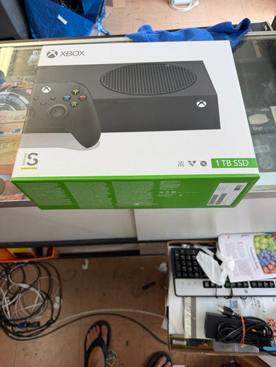 Xbox Series S 1TB SSD console retail box on a glass display counter in a retail store, with a controller pictured on the front of the packaging.