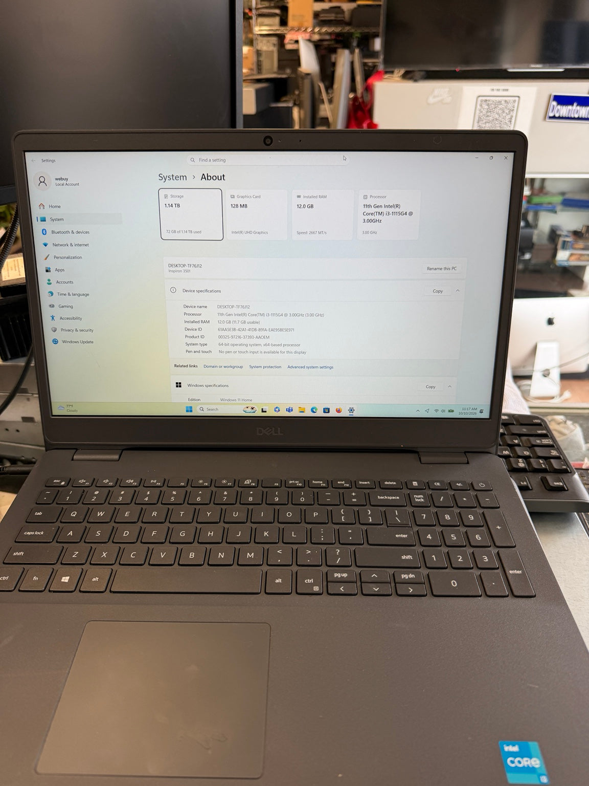 A Dell laptop with an Intel Core processor and Windows 11 Pro shown open on a desk, with a blurred office background.