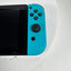 A close-up of a Nintendo Switch console with a bright turquoise blue Joy-Con controller attached, resting on a white surface.