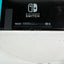 Nintendo Switch console photographed from above, showing the black back panel with the Nintendo Switch logo and small printed details, resting on a white surface.