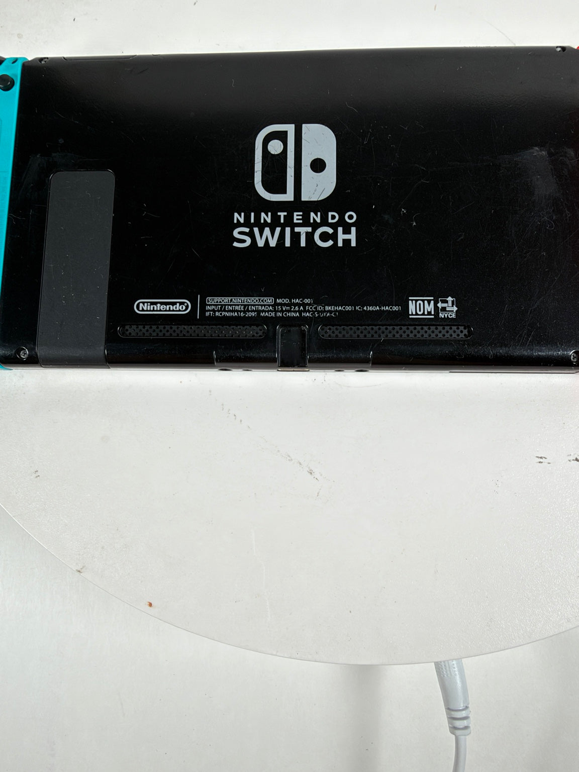 Nintendo Switch console photographed from above, showing the black back panel with the Nintendo Switch logo and small printed details, resting on a white surface.