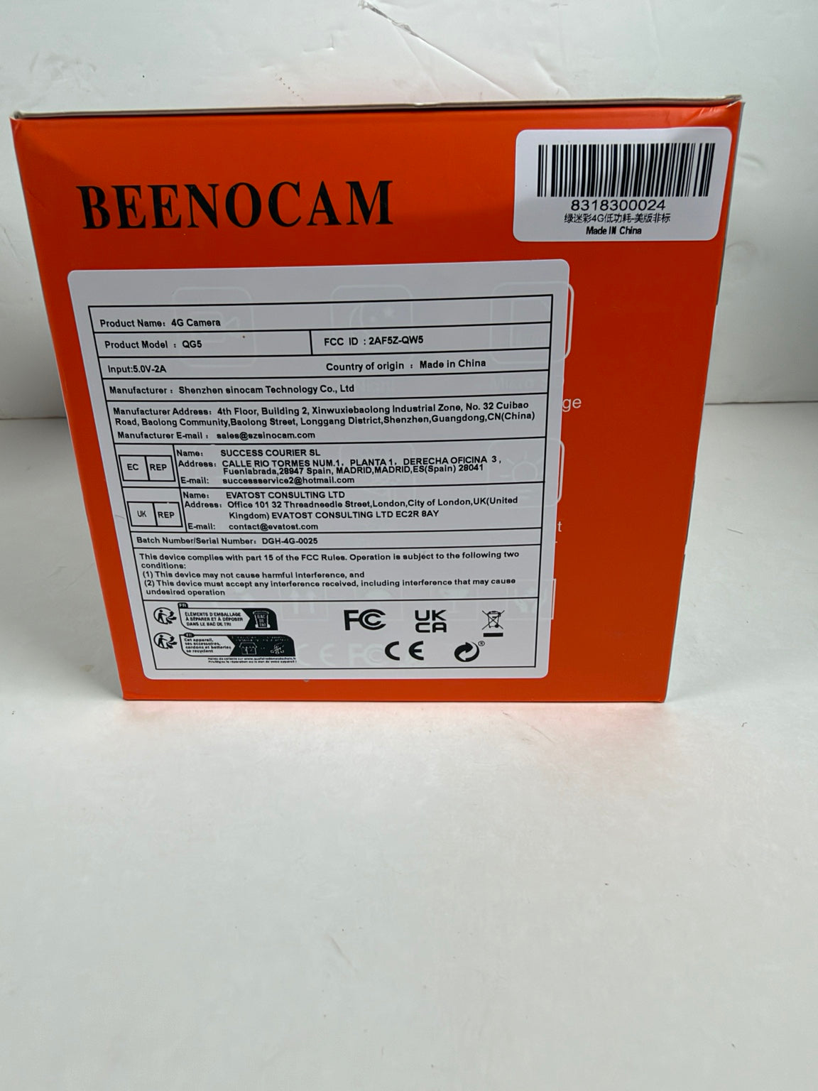 The back of an orange Beenocam product box with a barcode and printed specifications, photographed on a white surface.