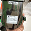 A hand holding a green camouflage-patterned UK plug-in 4G SIM card adapter device, showing the back with UK FC/CE certification stickers and a white instruction label.