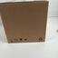 A plain brown cardboard box photographed on a white surface against a white wall, with handling icons and a recycling symbol printed near the bottom.