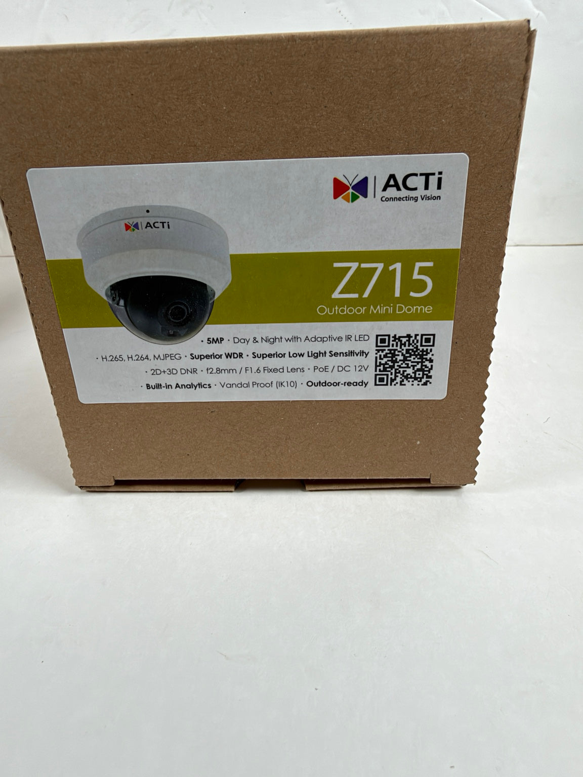 A brown cardboard product box for the ACTi Z715 Outdoor Mini Dome security camera, featuring a white and green product label on the front.