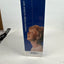A tall rectangular product box standing upright on a white surface against a white wall. The box is predominantly dark blue with vertical white text reading 'LIFE STARTS FROM HEARING' and a printed photo of a woman wearing a small ear device.