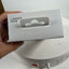 A hand holds a white Linner Nova product box in front of a white circular appliance base with a power cord plugged in.