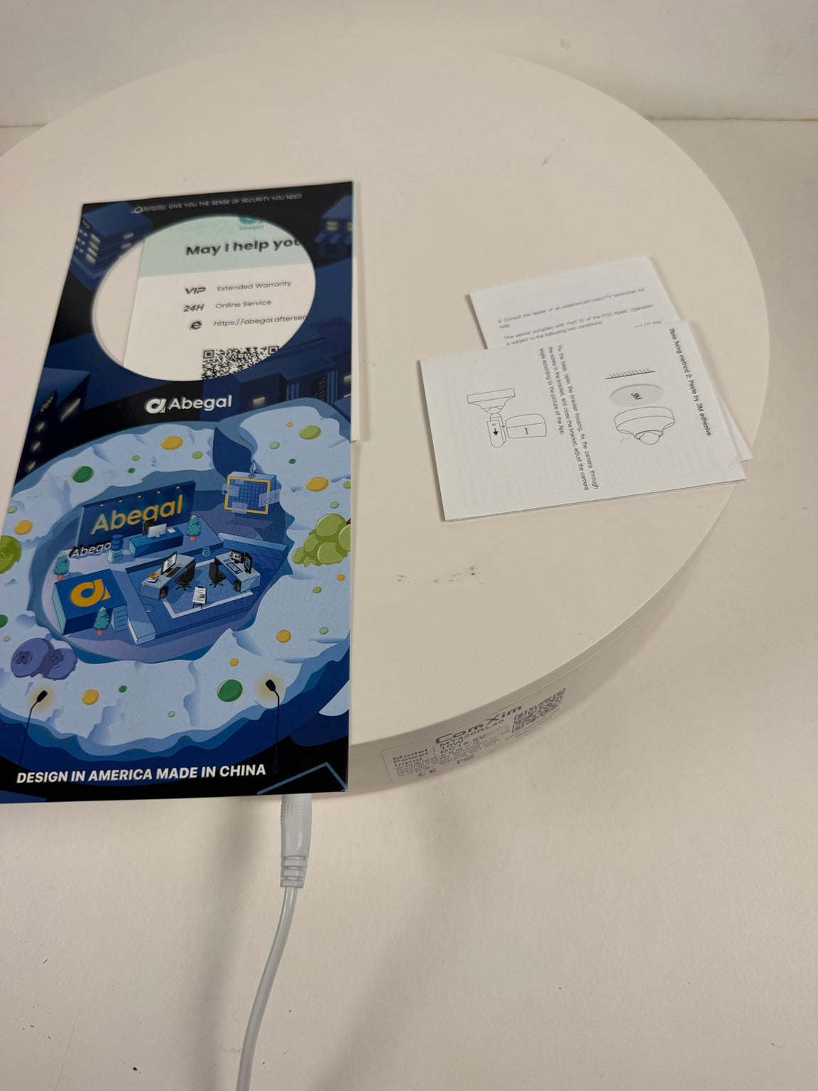 An Abegal 'Moyi I help you' USB-C adapter and its packaging are displayed on a white circular table alongside user manuals and a charging cable.