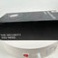A black rectangular product box with white text reading 'THE SECURITY YOU NEED' and 'Wireless Security' sits on top of a white round base or stand with a red switch and product label visible.