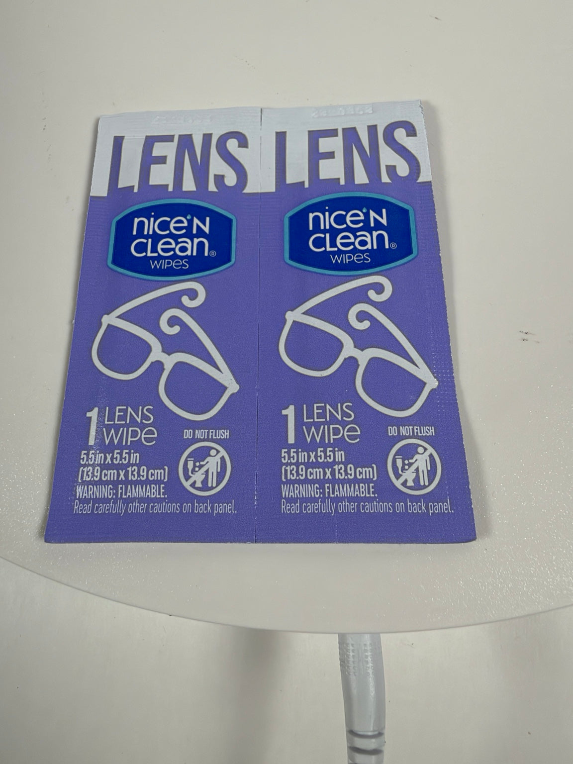 Two packages of Nice 'N Clean Lens Wipes on a white surface, with the purple packaging clearly showing the brand and product type.
