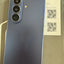 Samsung Galaxy Z Fold 3 smartphone shown from the back in a dark blue-gray color, resting on its original packaging box.