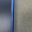 Close-up of a dark blue or black rectangular object with a thin metallic blue edge, positioned next to a textured gray surface.