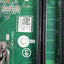 Close-up of a green printed circuit board showing a black PCIe slot, connector pins, white labeling stickers, and technical component markings.
