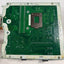 A green printed circuit board assembly with a central metal mounting bracket, photographed from above on a white surface.