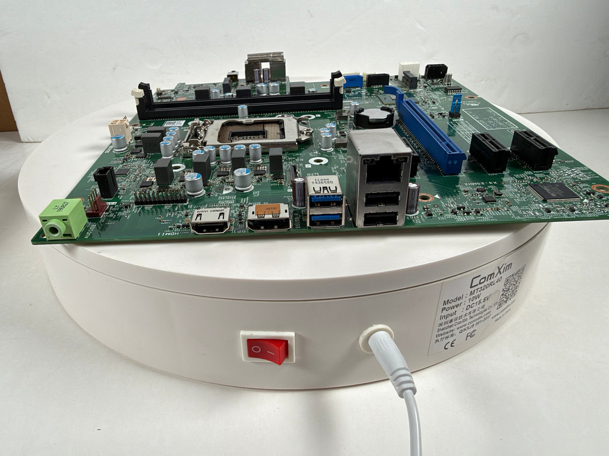 A green ComKit 4-in-1 industrial motherboard with multiple ports and components, displayed on a white circular rotating product stand.