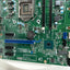 A green computer motherboard with an LGA1200 socket, RAM slots, a blue PCIe slot, and various electronic components, photographed from above on a white background.