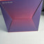 A square product box with a purple and pink gradient design, photographed on a light gray surface.