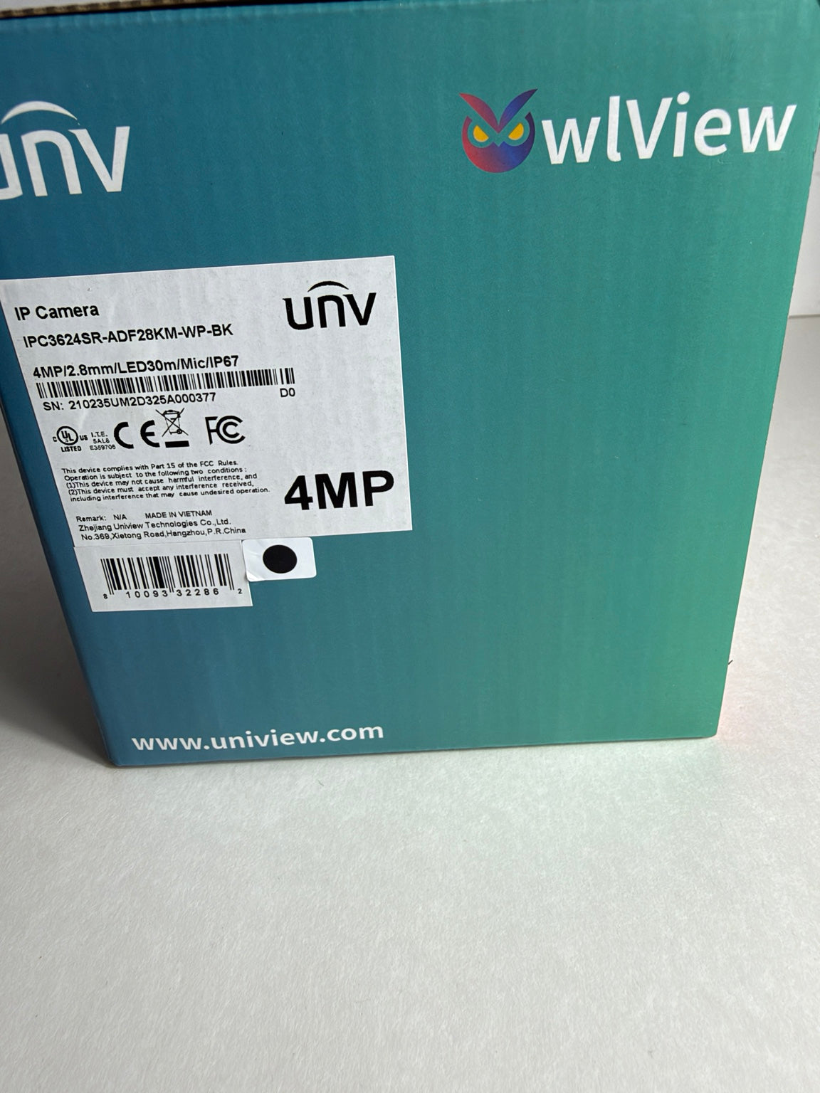 A close-up of the back of a teal UniView IP Camera box, showing the UniView logo, a white product label with barcodes and '4MP' text, and the website www.uniview.