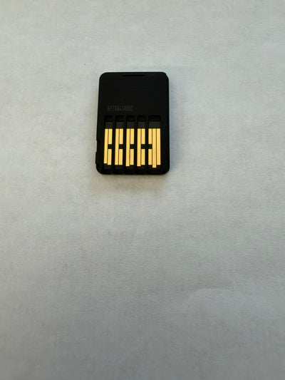 A small black rectangular electronic component with five gold metal contacts on a light gray textured background.